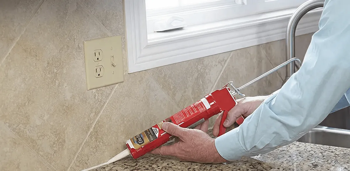 Handyman applying caulk along a kitchen backsplash and countertop seam in Clearwater, FL